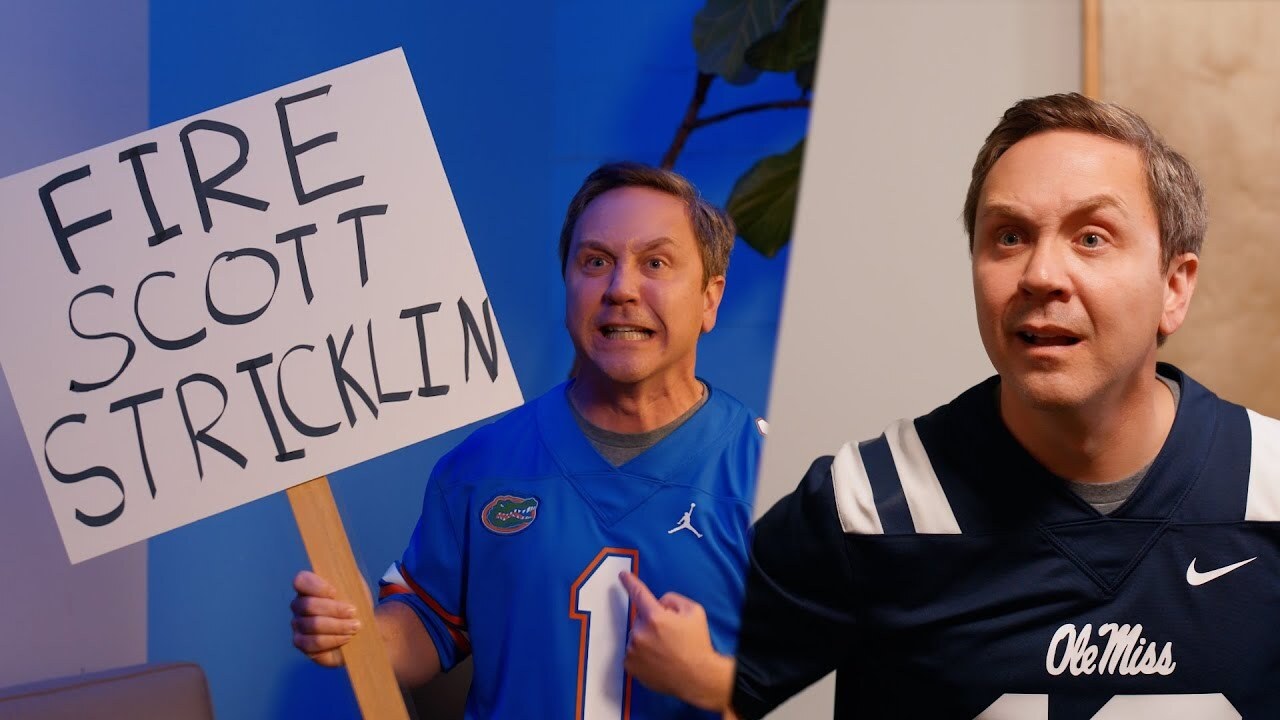 guy in an ole miss jersey and guy in a florida gators jersey with a sign