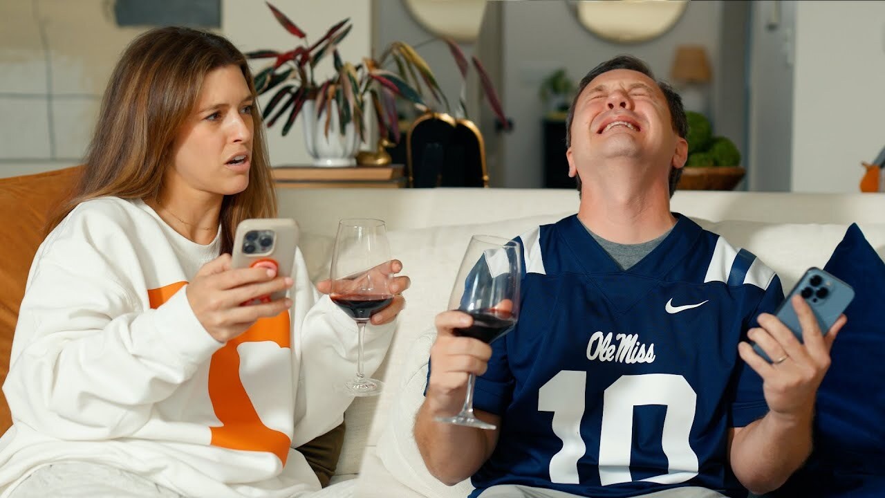 guy crying in an ole miss jersey and girl in a tennessee sweatshirt holding glasses of wine