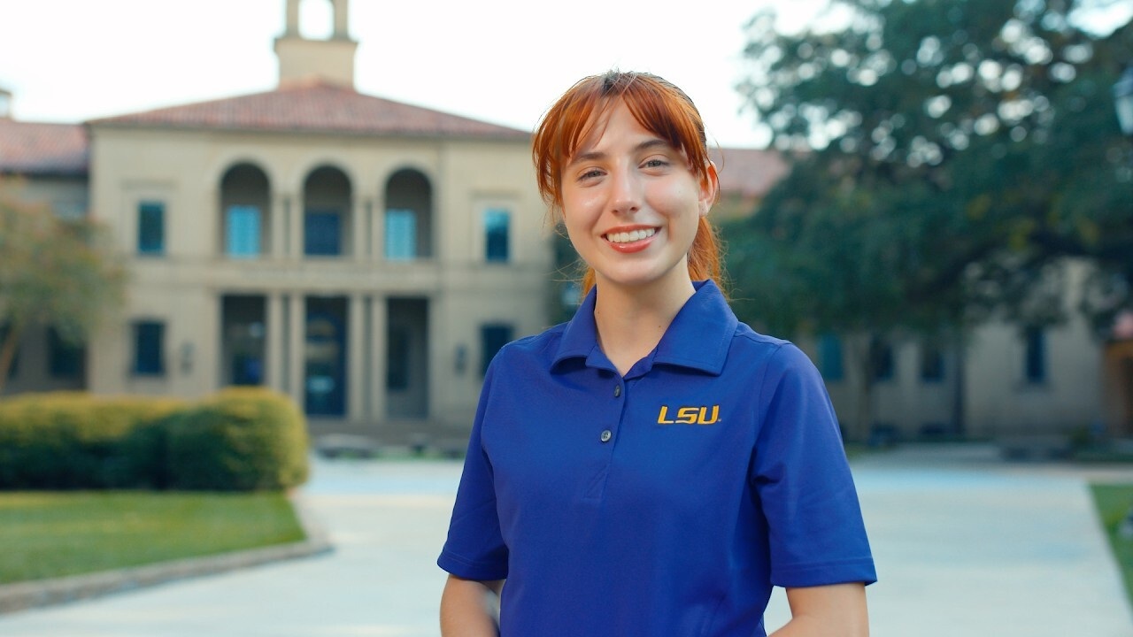 girl smiling wearing a polo that says LSU