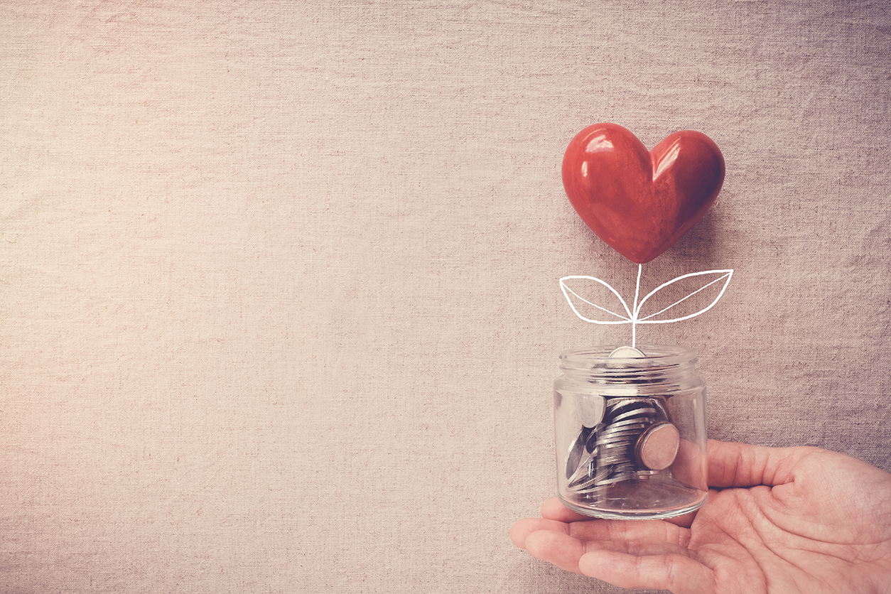 Hand holding a jar of coins that blooms into a heart