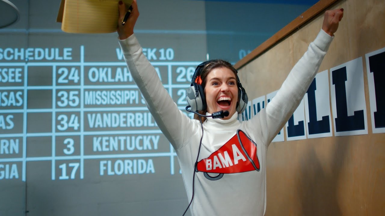 Alabama Cheerleader cheering with a headset and clipboard in hand
