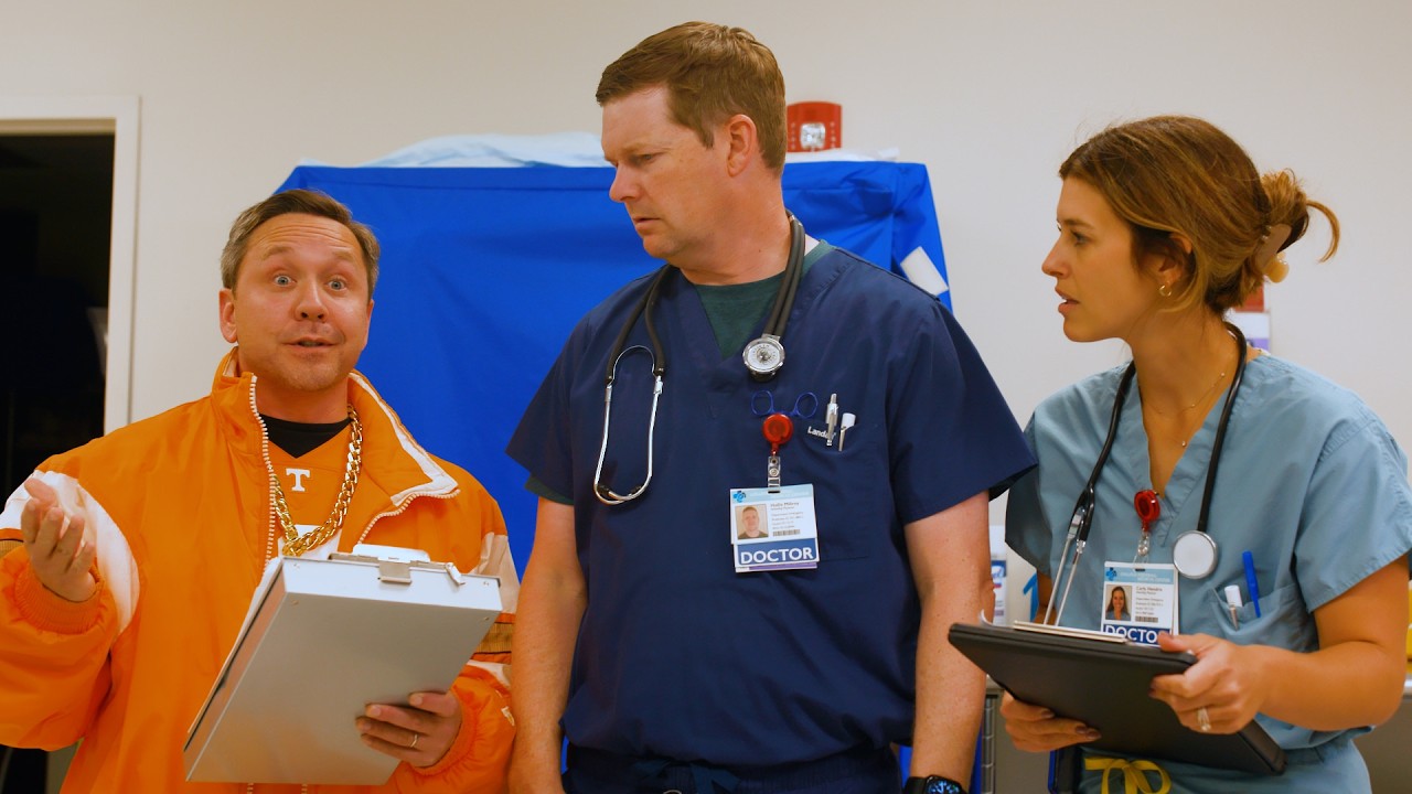 two nurses with clipboards and badges stand next to person in Tennessee gear